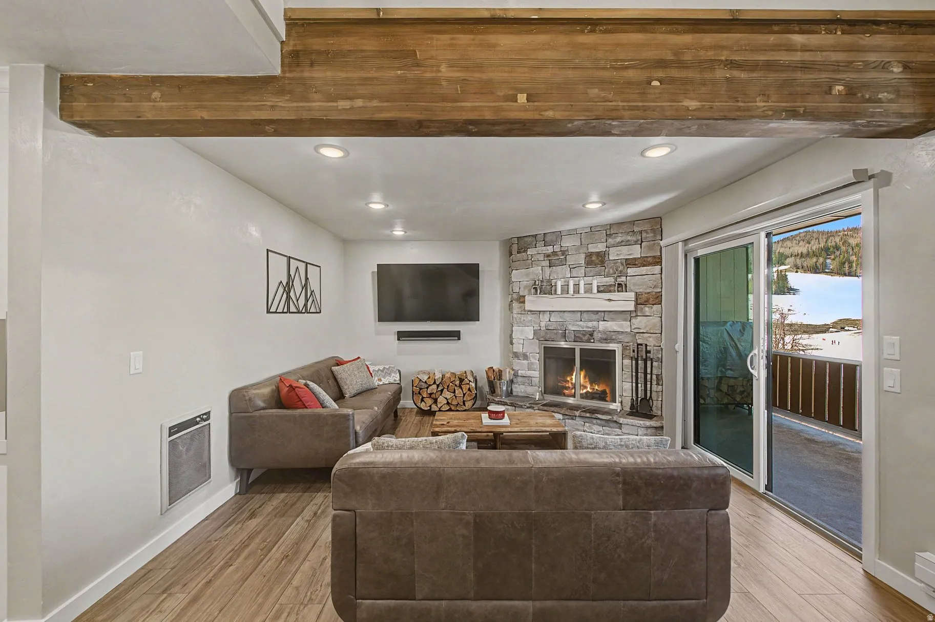 Living room featuring light wood-style floors, a fireplace, heating unit, and recessed lighting