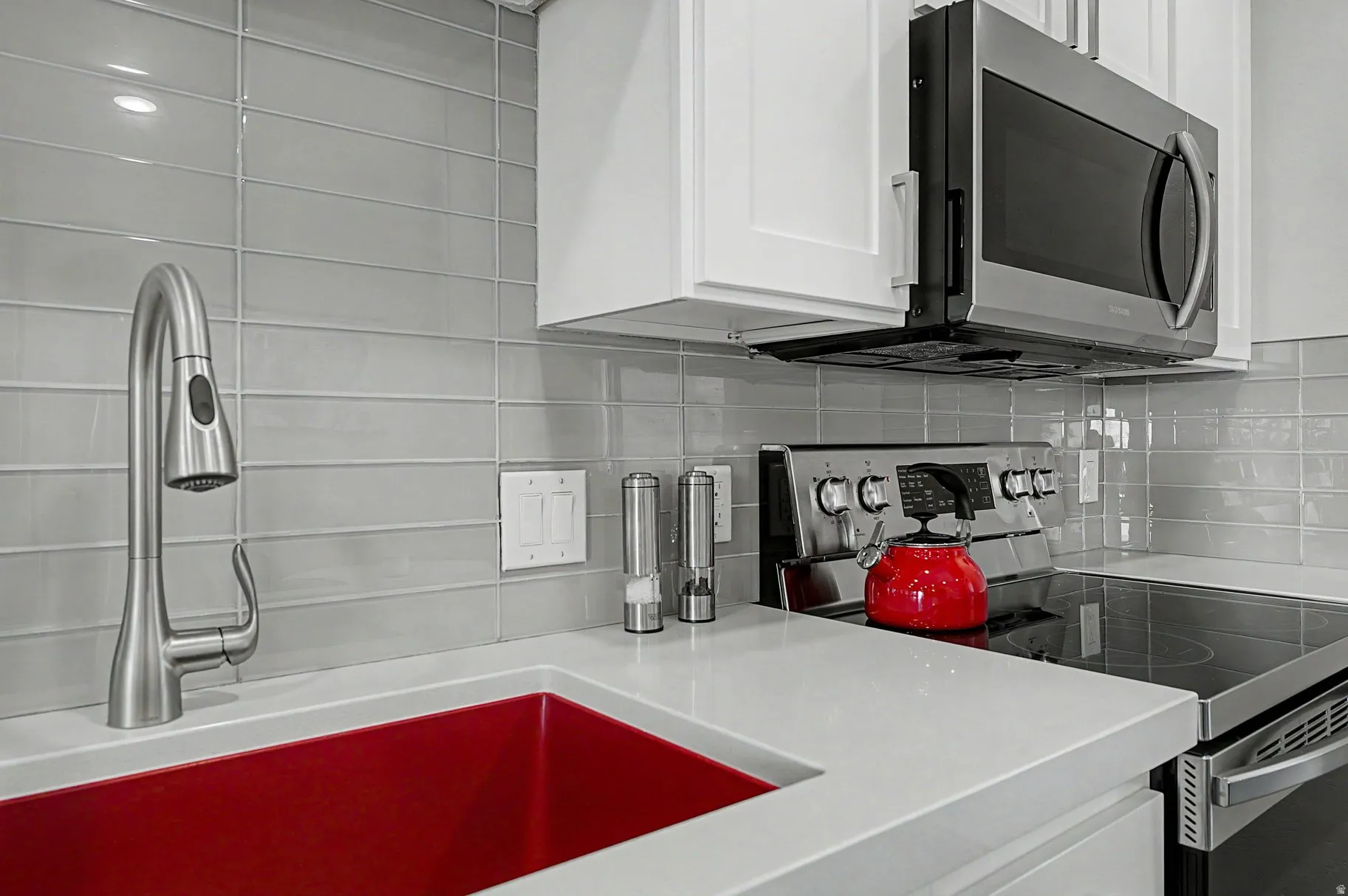 Kitchen featuring stainless steel appliances, white cabinetry, and decorative backsplash