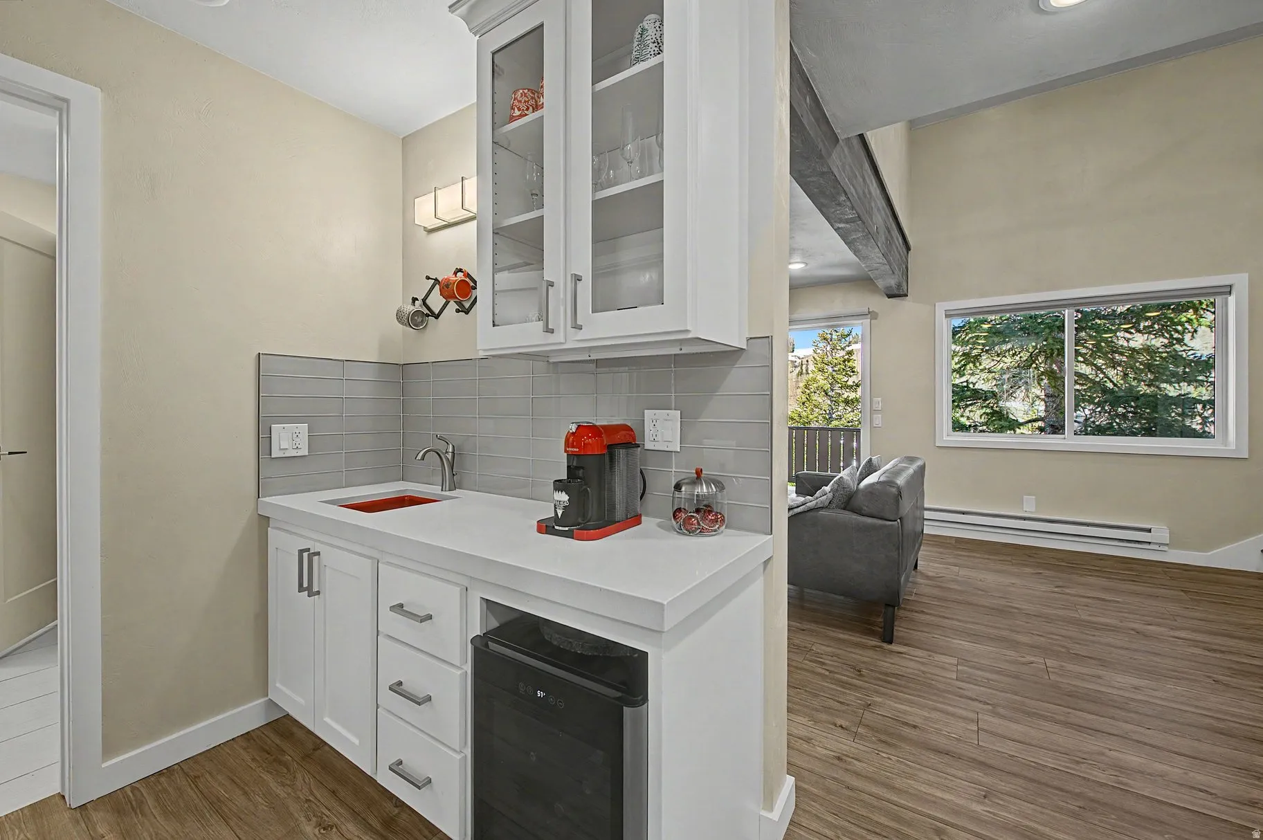 Bar area with white cabinetry, beverage cooler, glass insert cabinets, dark wood-type flooring, and a baseboard radiator