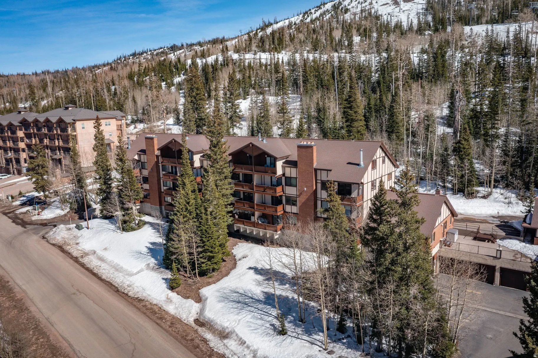 Snowy aerial view featuring a mountain view and a view of apartment building / complex
