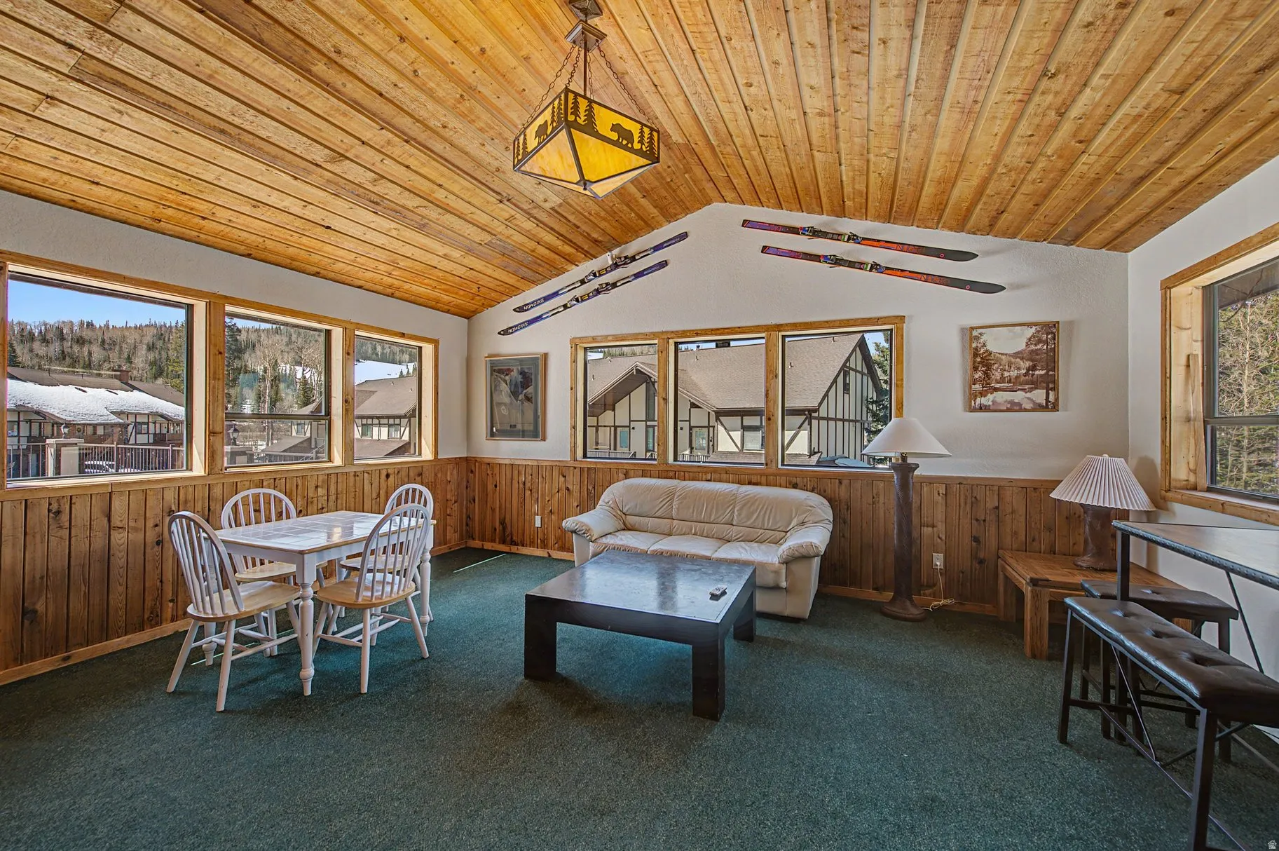 Living room with wooden walls, wooden ceiling, wainscoting, and carpet