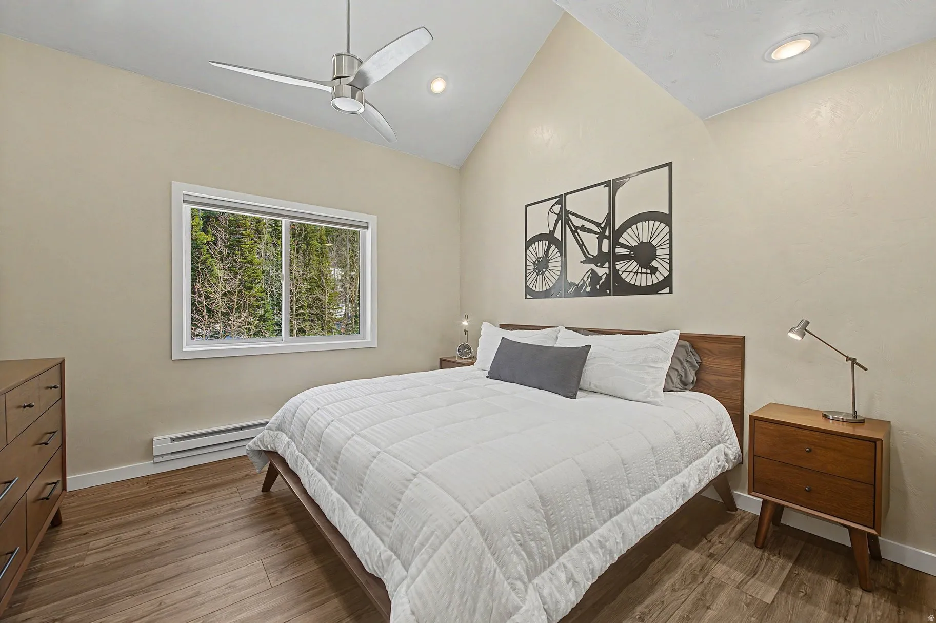 Bedroom with a baseboard heating unit, vaulted ceiling, dark wood-style flooring, ceiling fan, and recessed lighting