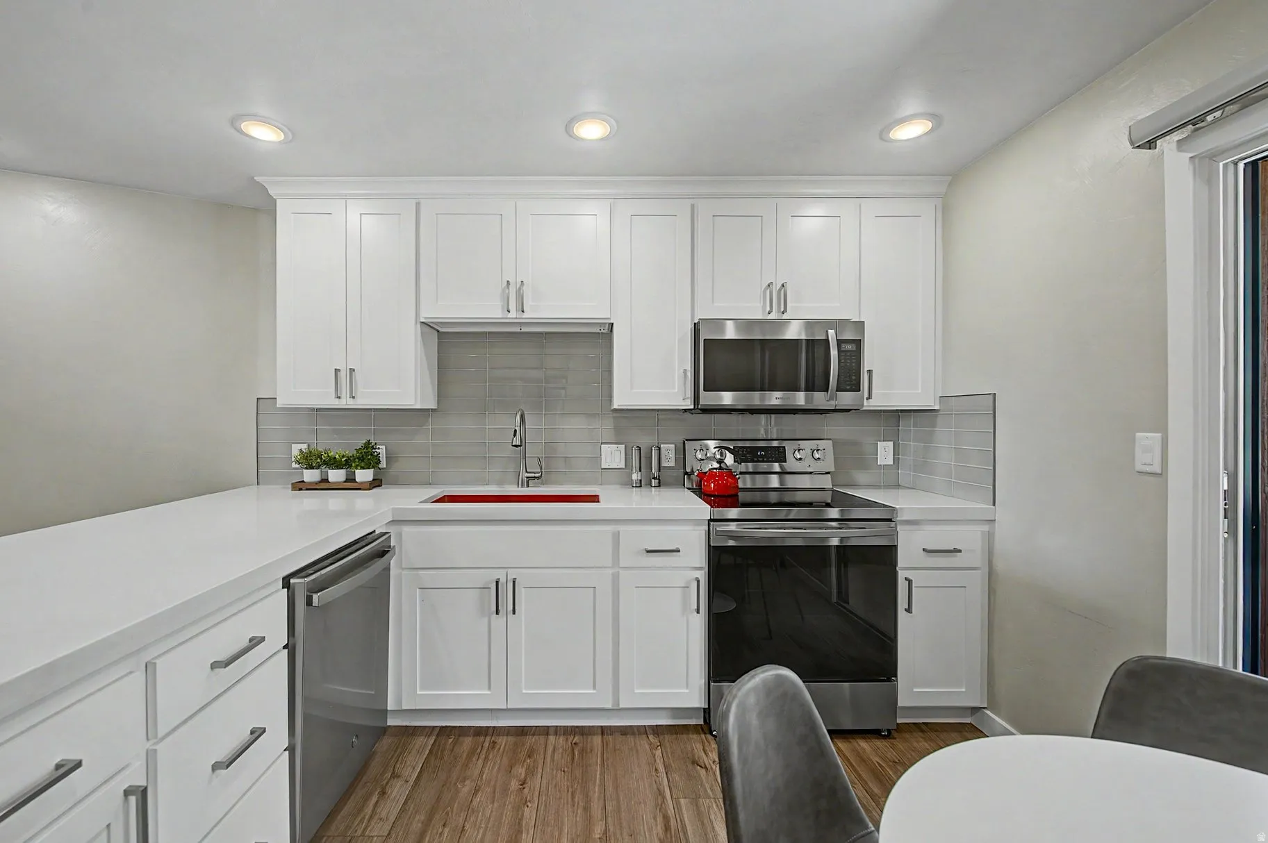 Kitchen featuring stainless steel appliances, white cabinetry, light wood-style flooring, tasteful backsplash, and recessed lighting