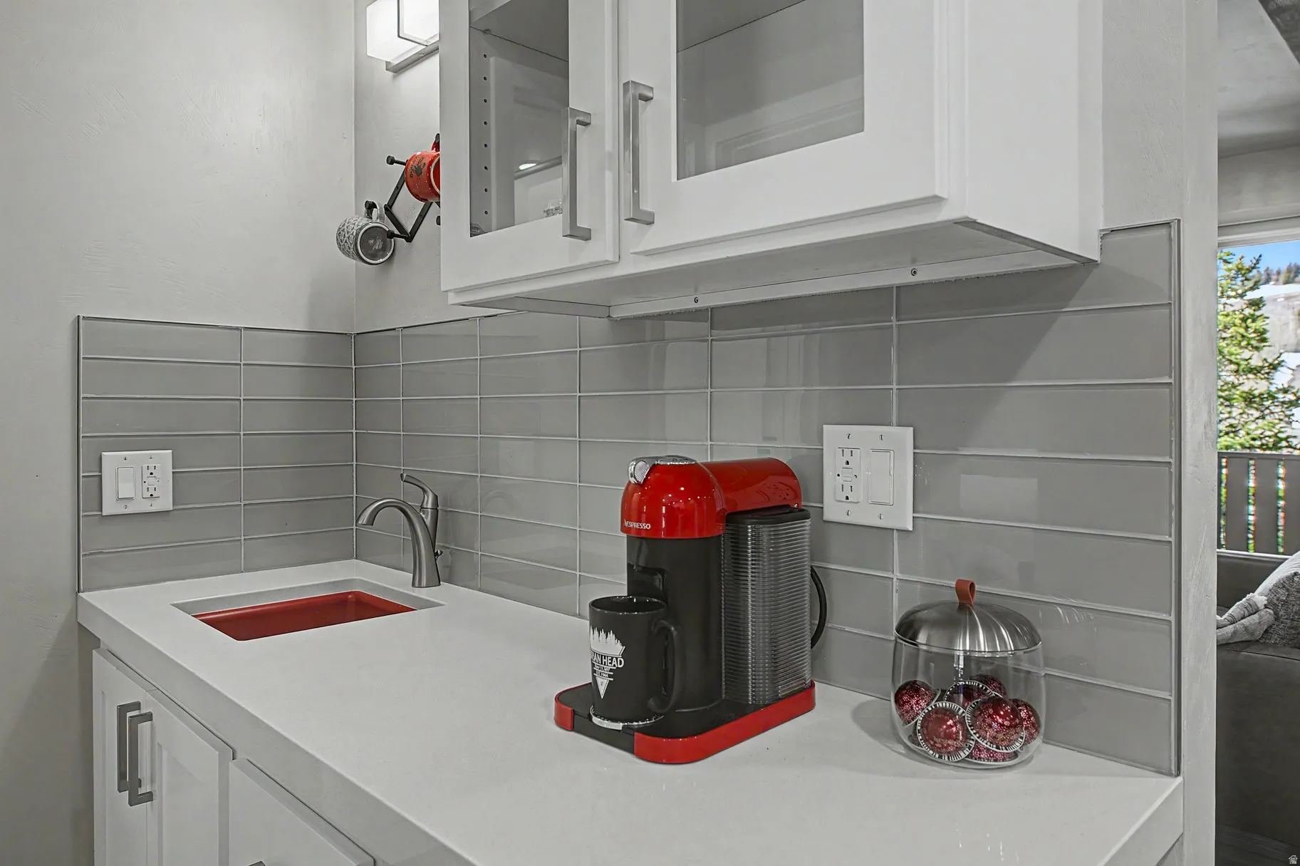 Kitchen with white cabinetry, tasteful backsplash, glass fronted cabinets, and light stone countertops
