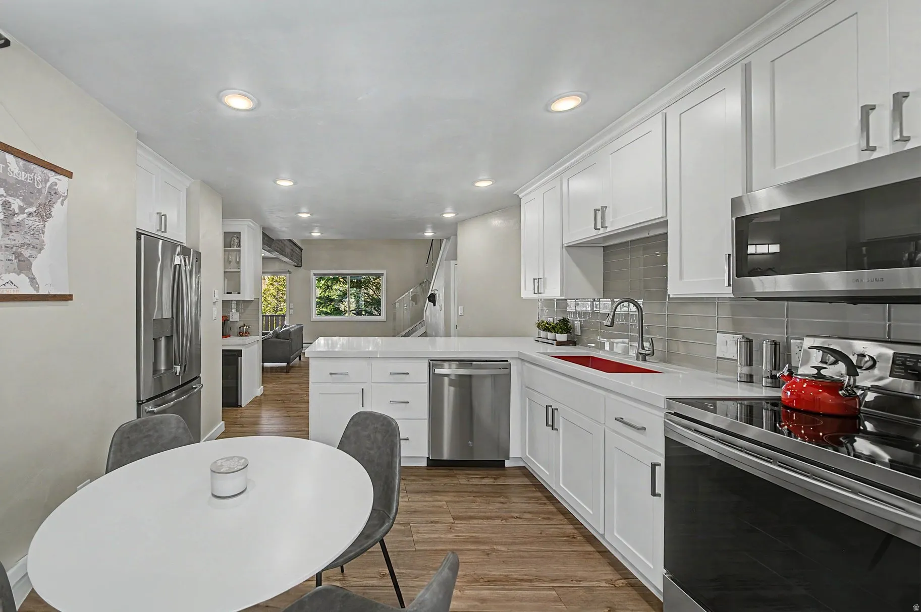 Kitchen featuring stainless steel appliances, white cabinets, a peninsula, dark wood-style floors, and decorative backsplash