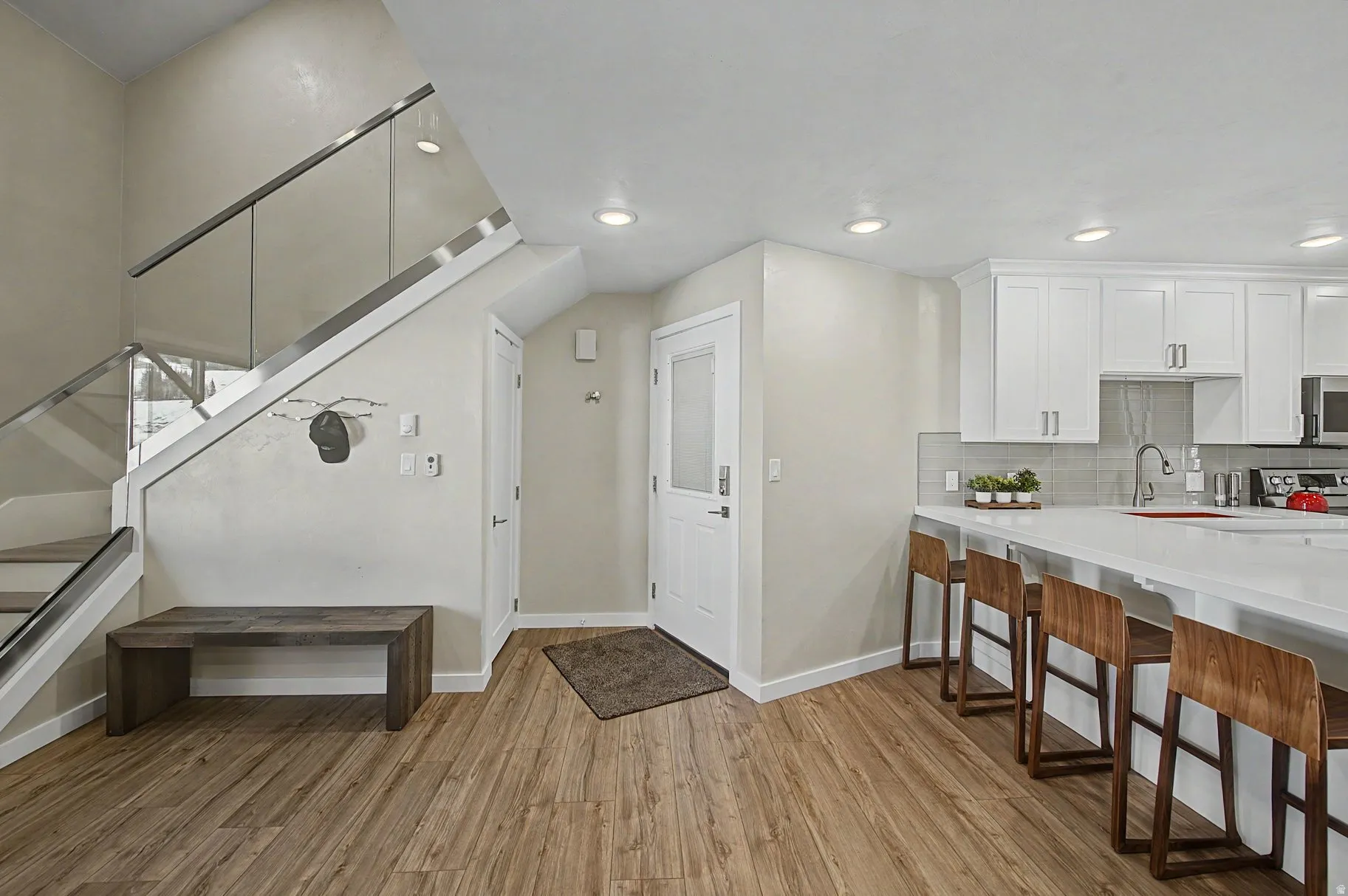 Kitchen featuring a breakfast bar, white cabinets, light wood finished floors, decorative backsplash, and recessed lighting