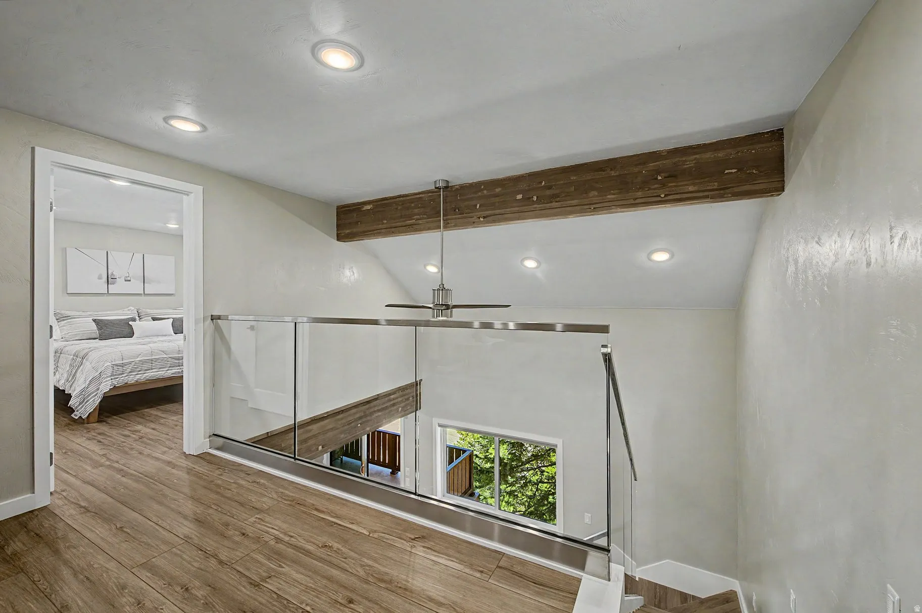 Hall with an upstairs landing, lofted ceiling with beams, recessed lighting, wood finished floors, and healthy amount of natural light