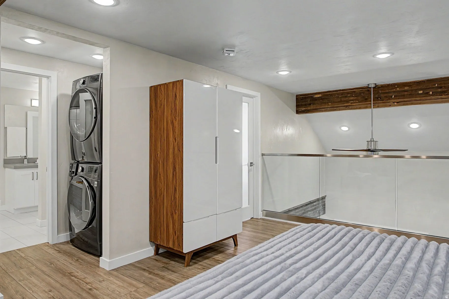 Bathroom with light wood-type flooring, recessed lighting, stacked washer and dryer, and vaulted ceiling