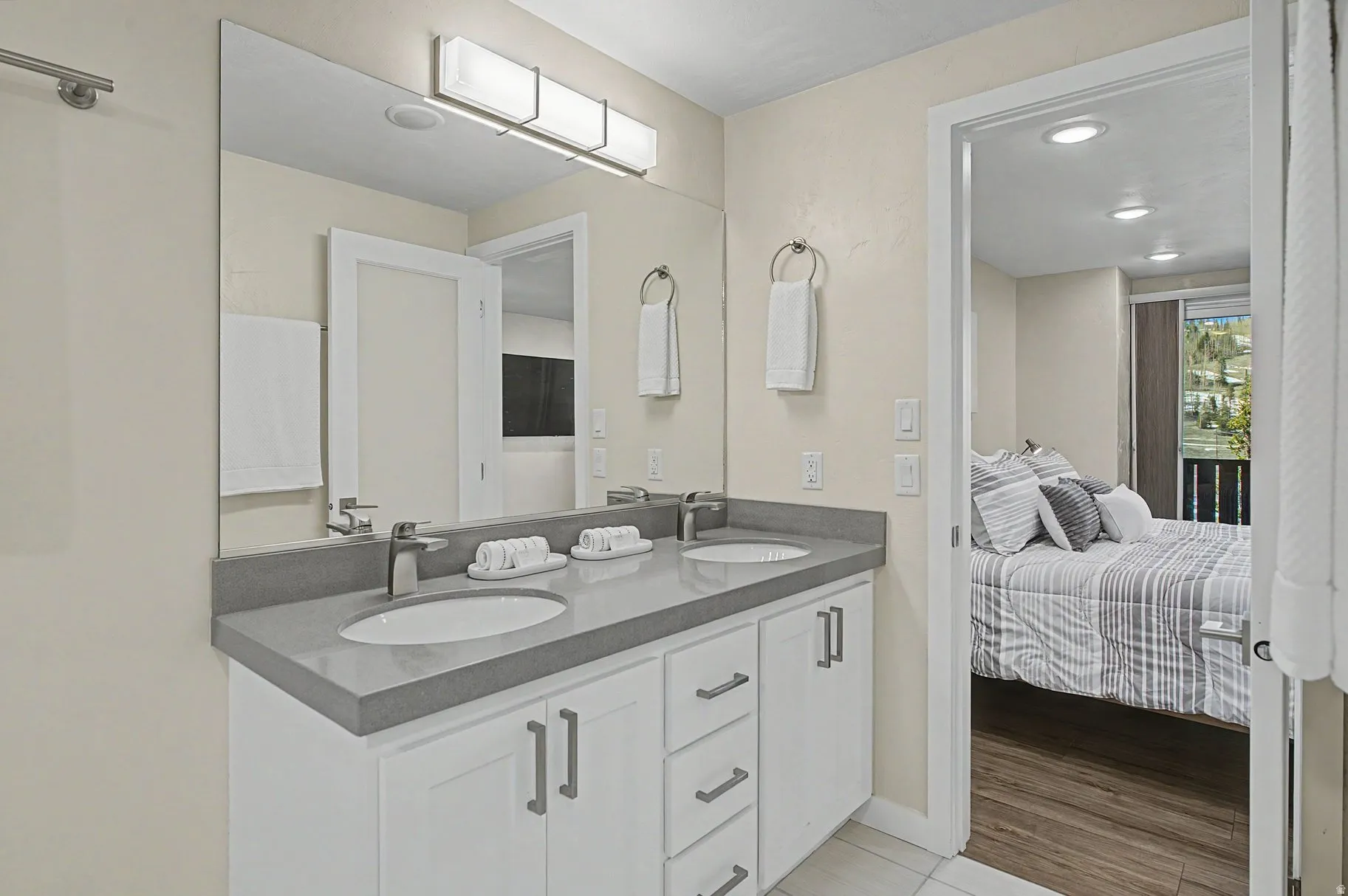 Ensuite bathroom with double vanity, recessed lighting, and light wood-type flooring