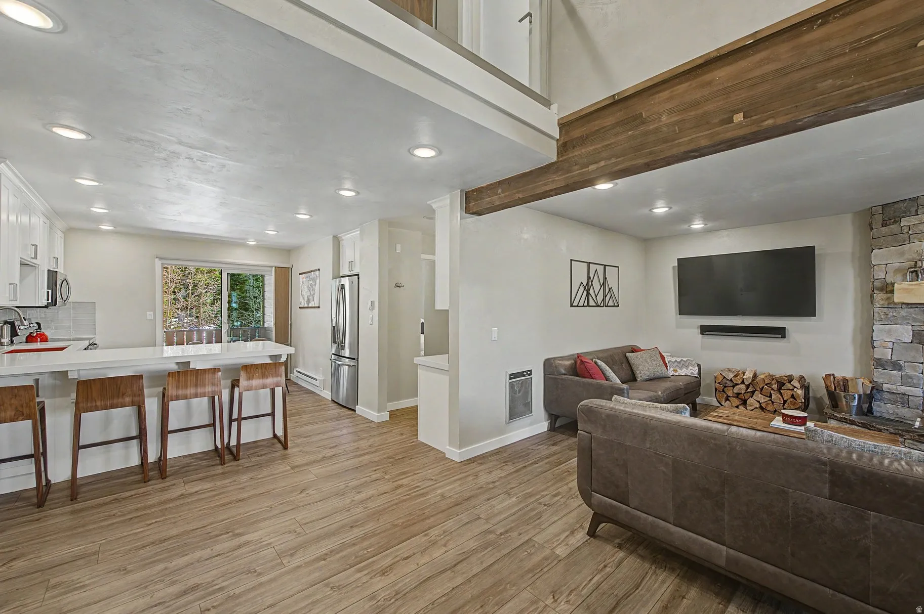 Living area with light wood-type flooring, heating unit, recessed lighting, and baseboard heating