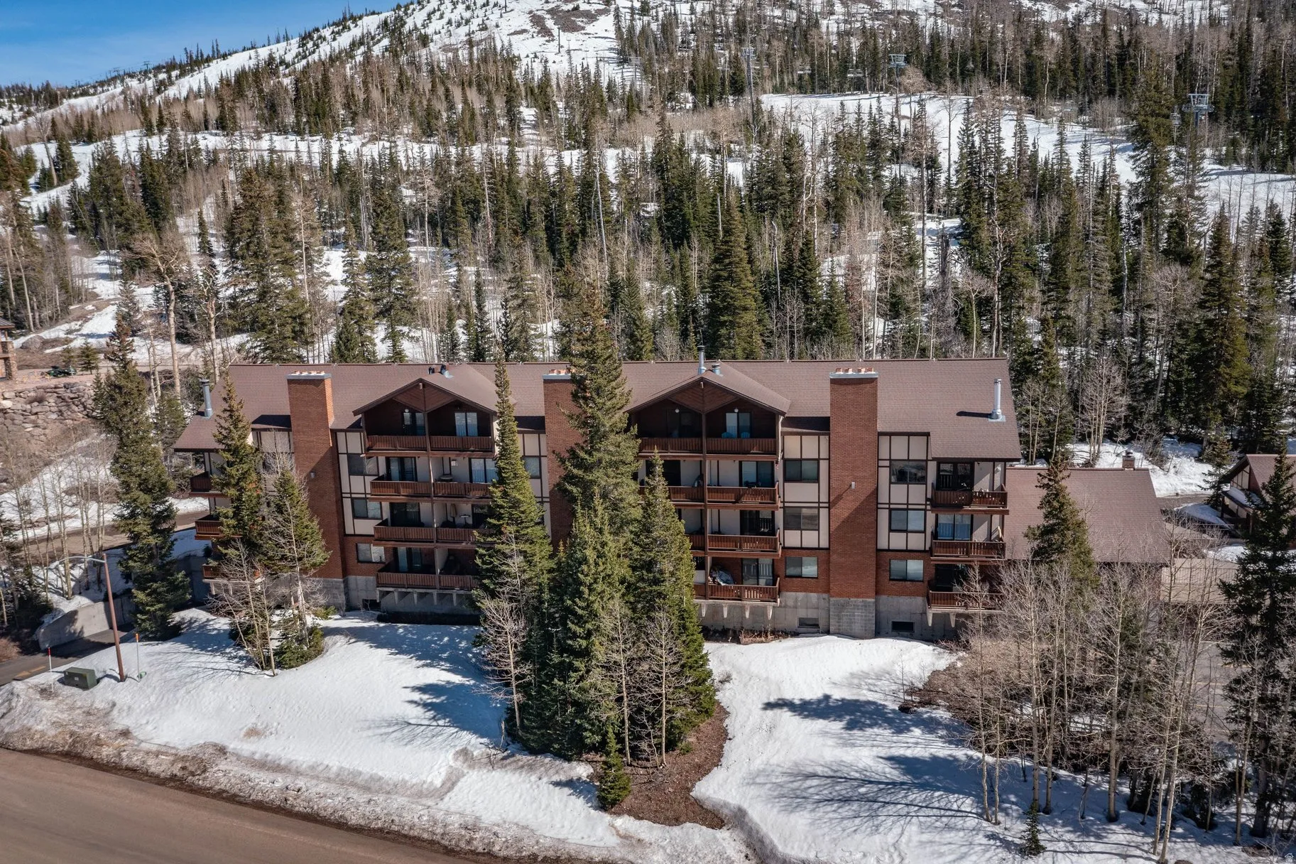 Snow covered property featuring a mountain view and a view of apartment building / complex