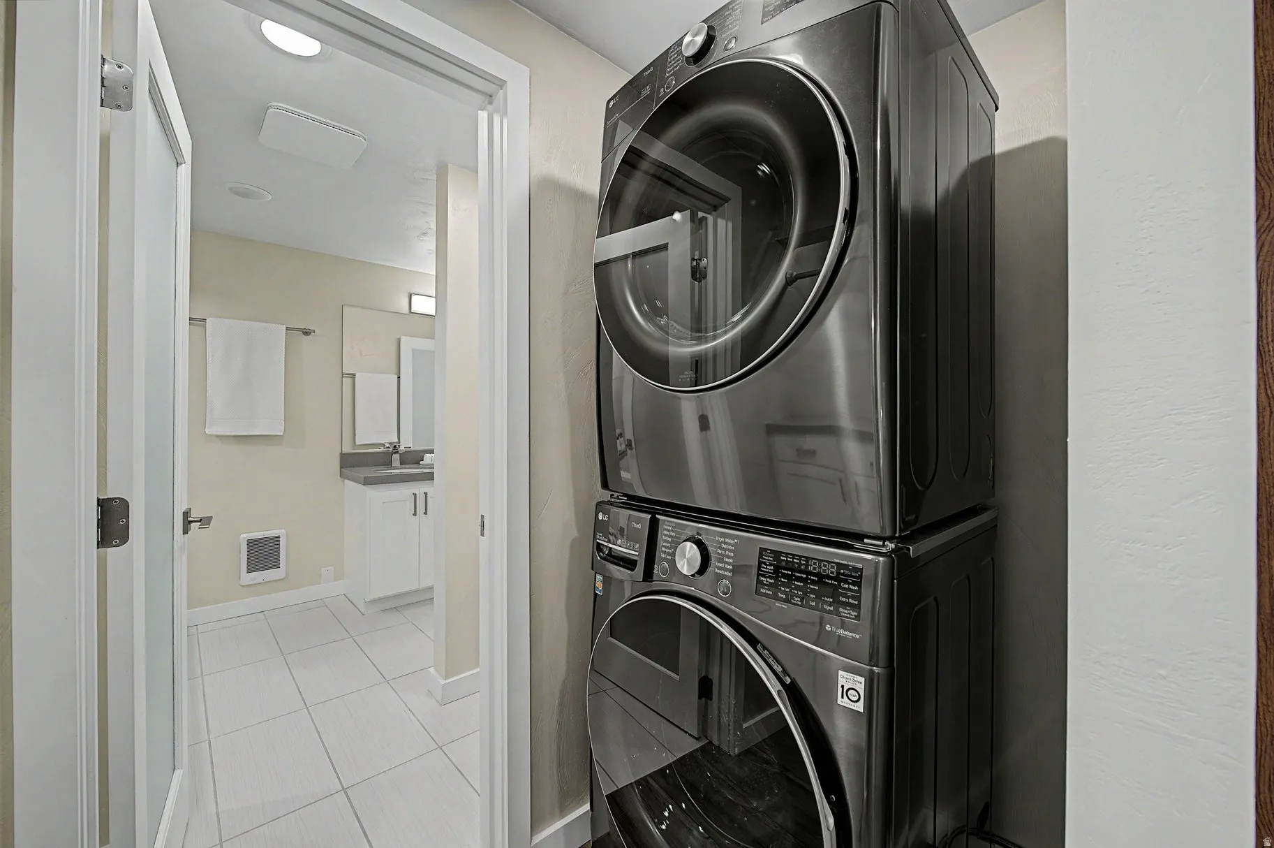 Laundry area with light tile patterned flooring and stacked washer / drying machine