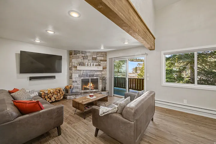 Living room with hardwood / wood-style floors, baseboard heating, a stone fireplace, and recessed lighting