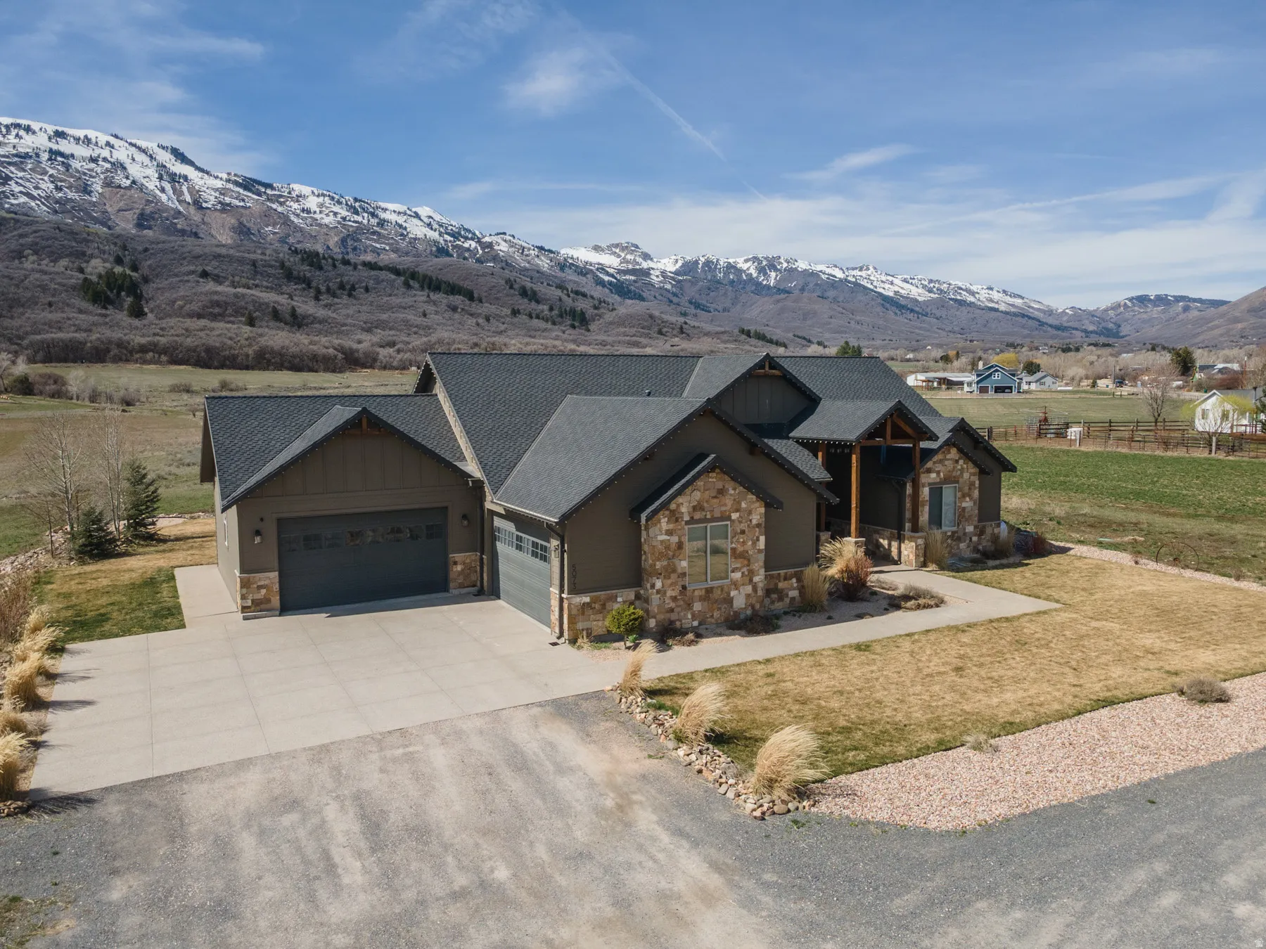 Craftsman house with stone siding, a garage, driveway, and a front lawn