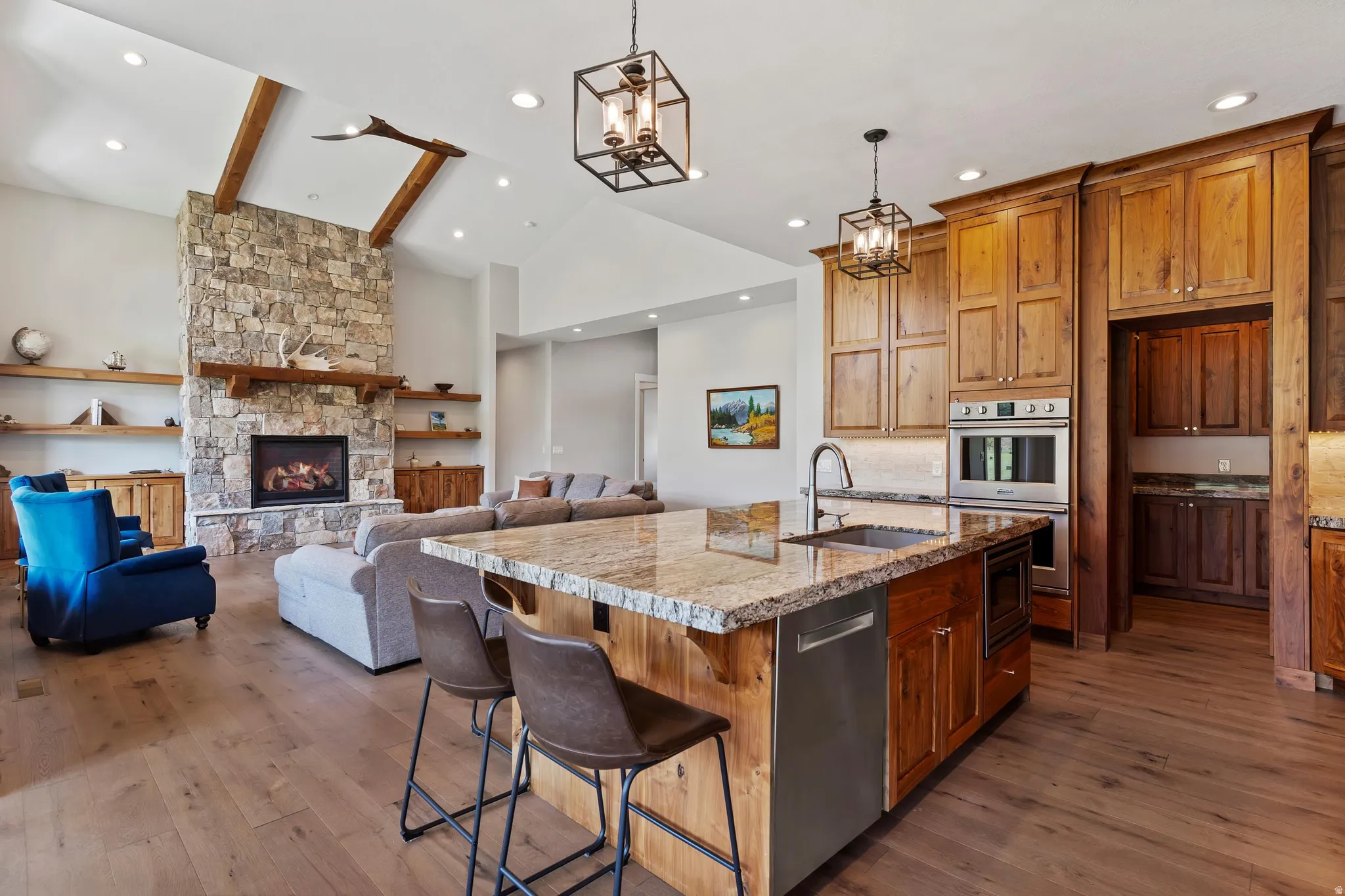Kitchen with gas range, custom walnut wood cabinets, granite and large island. Opening to living room.
