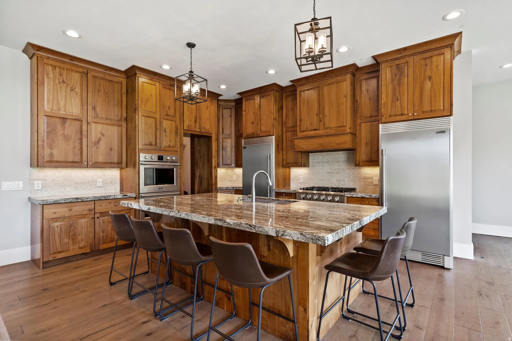 Kitchen with gas range, custom walnut wood cabinets, granite and large island.