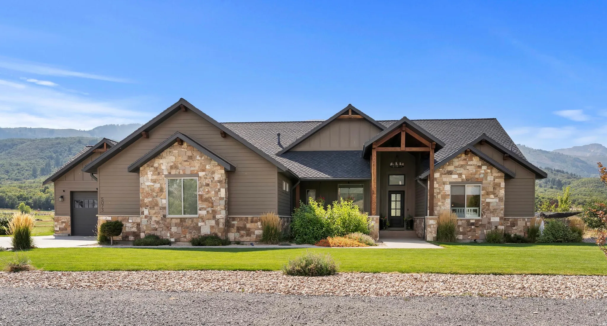 Craftsman inspired home with a mountain view, stone siding, custom timber beams.