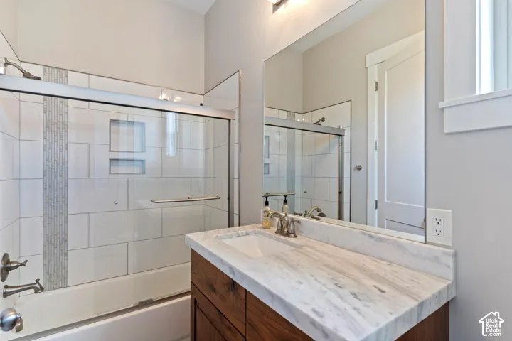 Full bath featuring vanity and shower / bath combination with glass door