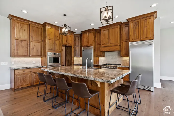 Kitchen with gas range, custom walnut wood cabinets, granite and large island.