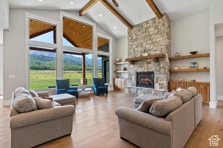 Living area featuring light wood finished floors, a stone fireplace, a mountain view, and lofted ceiling