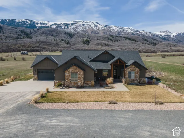 Craftsman-style home with stone siding, a front lawn, driveway, and a mountain view