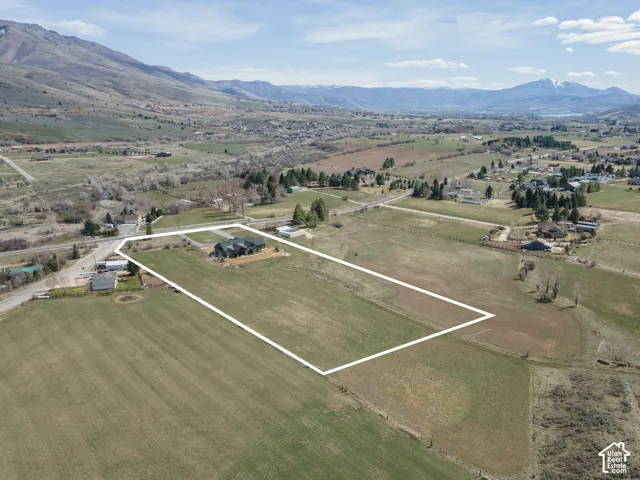 Aerial view of property and surrounding area with mountains, property parcel outlined, and rural landscape