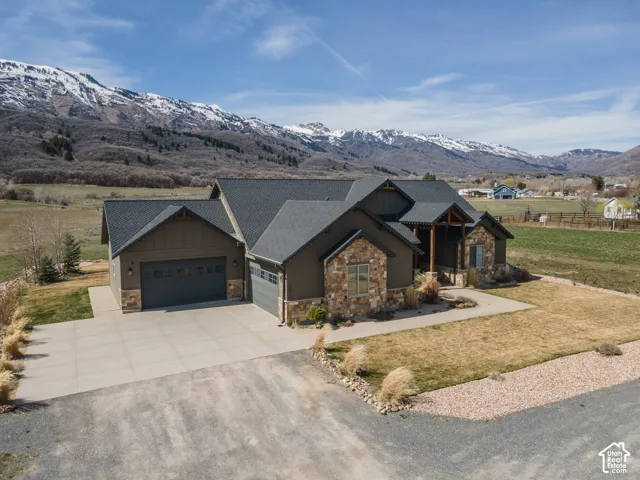 Craftsman house with stone siding, a garage, driveway, and a front lawn