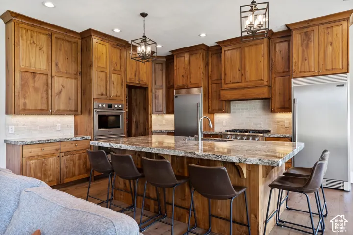 Kitchen with gas range, custom walnut wood cabinets, granite and large island.