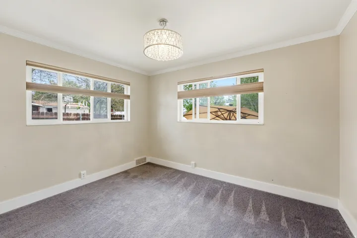Empty room featuring a chandelier, carpet floors, and crown molding