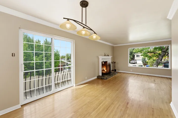 Unfurnished living room with crown molding, light wood-type flooring, and a lit fireplace
