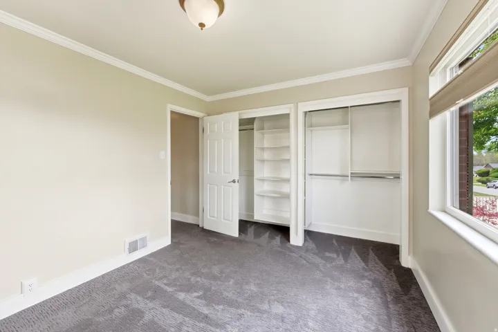 Unfurnished bedroom with multiple closets, dark carpet, and crown molding