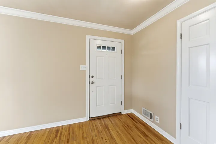 Entryway with crown molding and light wood-style floors