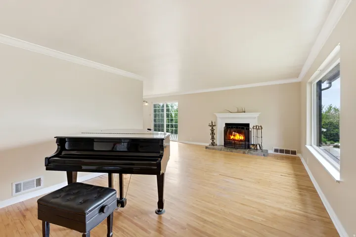 Sitting room with light wood-style floors, a lit fireplace, and crown molding