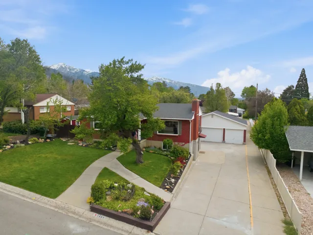 Ranch-style home featuring an outdoor structure, a garage, a chimney, a front yard, and a mountain view