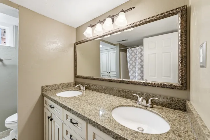 Bathroom featuring double vanity, a shower with shower curtain, and a textured wall