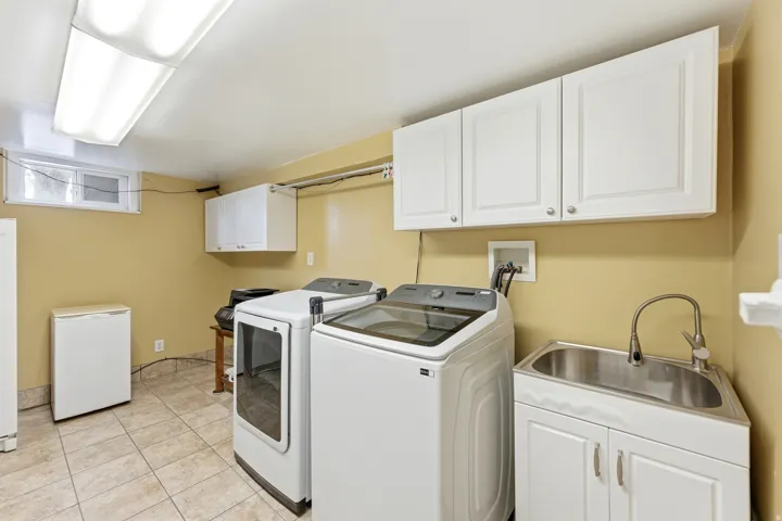 Laundry room with cabinet space, washer and dryer, and light tile patterned floors