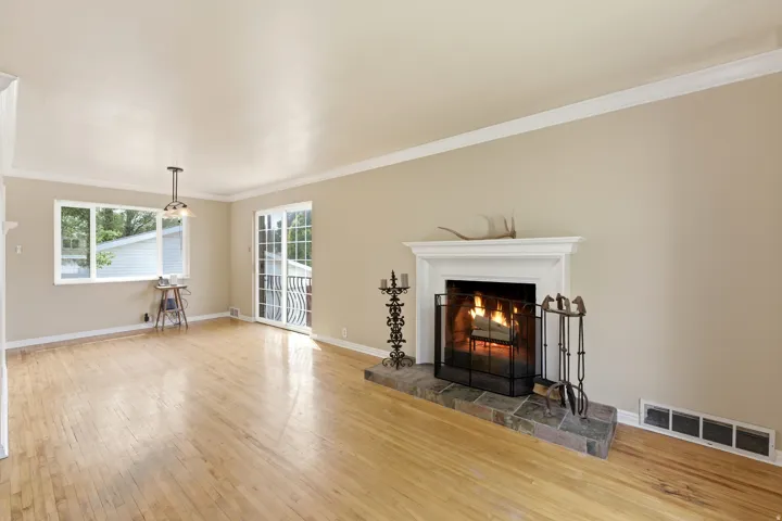 Unfurnished living room featuring light wood-type flooring, crown molding, and a warm lit fireplace