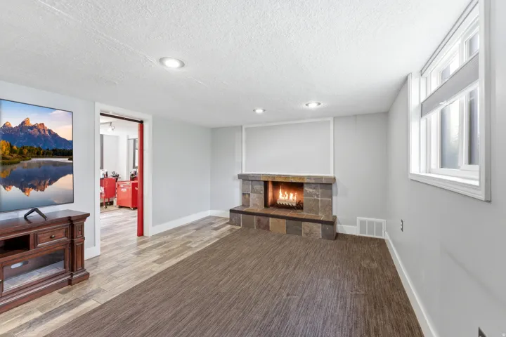 Unfurnished living room with a stone fireplace, a textured ceiling, wood finished floors, a mountain view, and recessed lighting