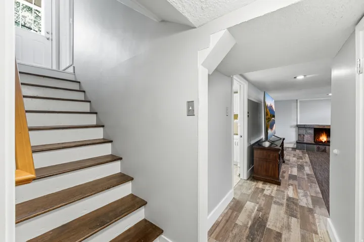 Stairway with wood finished floors, a fireplace, and a textured ceiling