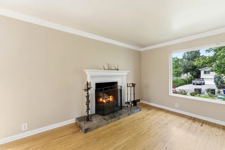 Living room with light wood-style floors, ornamental molding, and a tiled fireplace