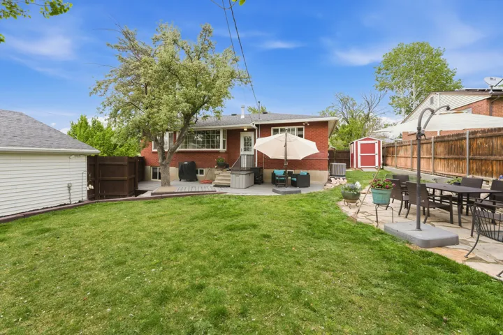Rear view of property featuring a shed, a patio, outdoor dining area, and a fenced backyard