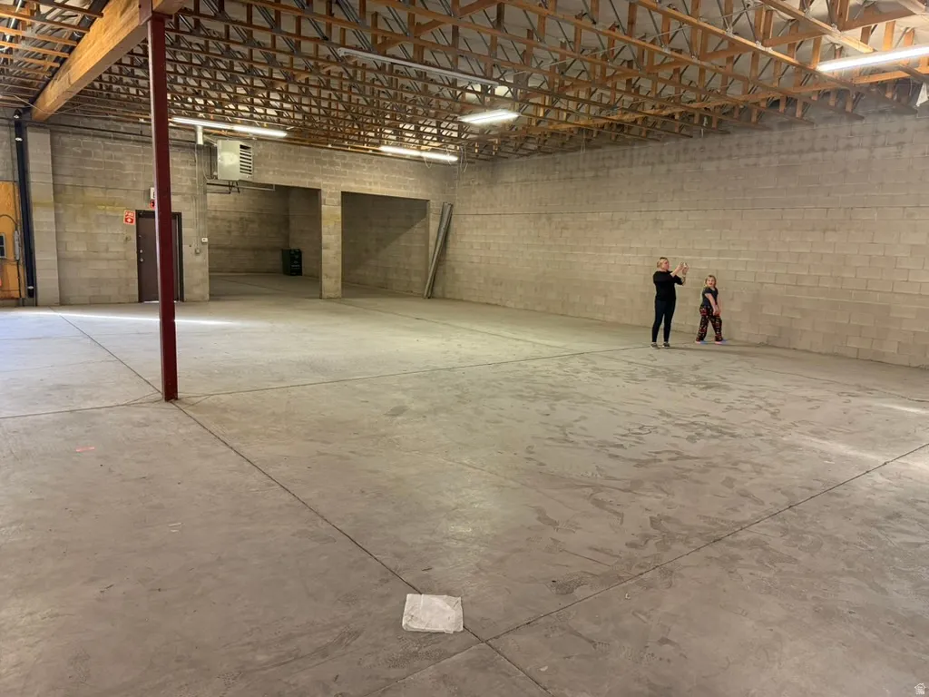 Garage featuring a heating unit and concrete block wall
