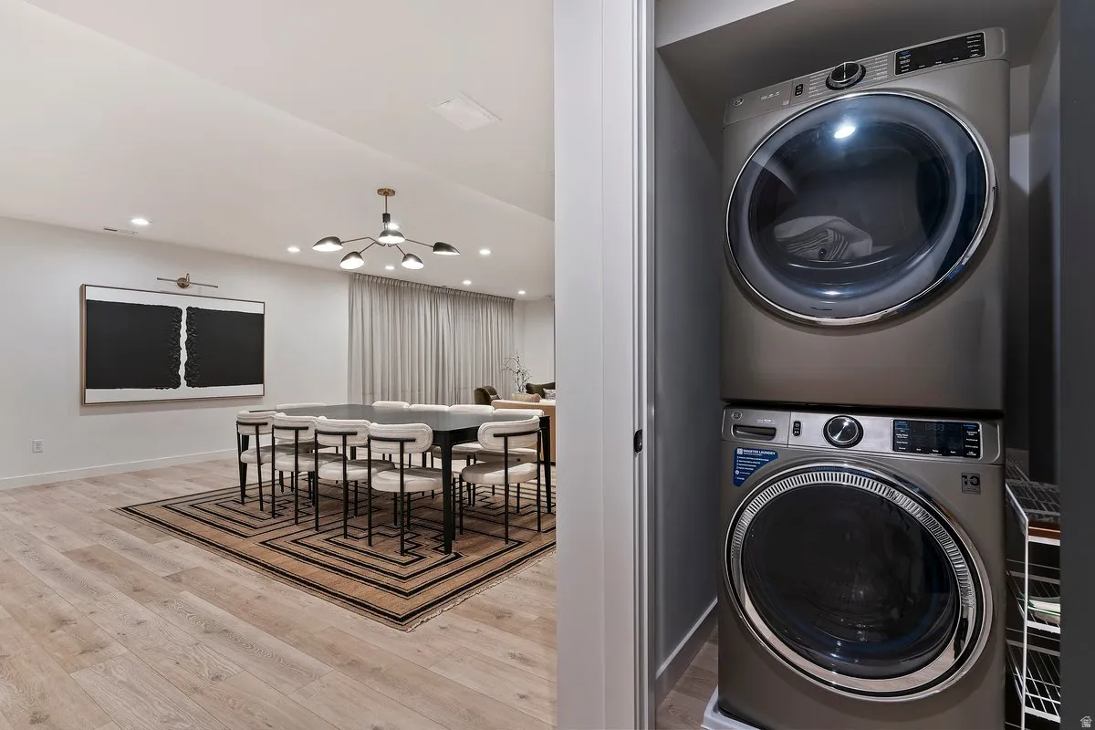 Laundry area featuring stacked washer / dryer, light wood-style floors, and suspended lighting