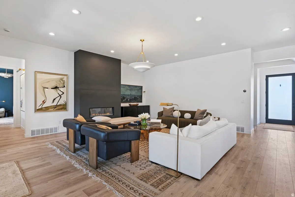 Living room with recessed lighting, light wood-type flooring, and a fireplace
