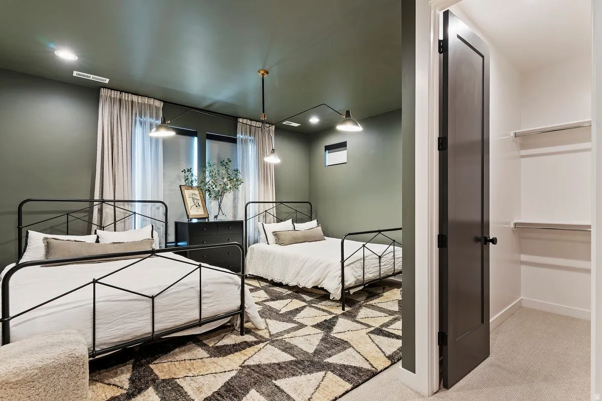 Bedroom with light colored carpet, recessed lighting, and a walk in closet