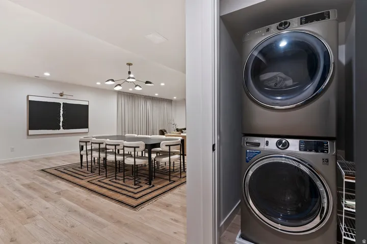 Laundry area featuring stacked washer / dryer, light wood-style floors, and suspended lighting