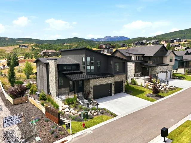 Modern multi-level residence featuring a dark-toned exterior with stone accents and multiple large windows