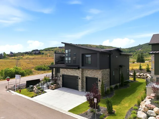 Contemporary residence featuring a dark exterior, stone accents, and a multi-level design