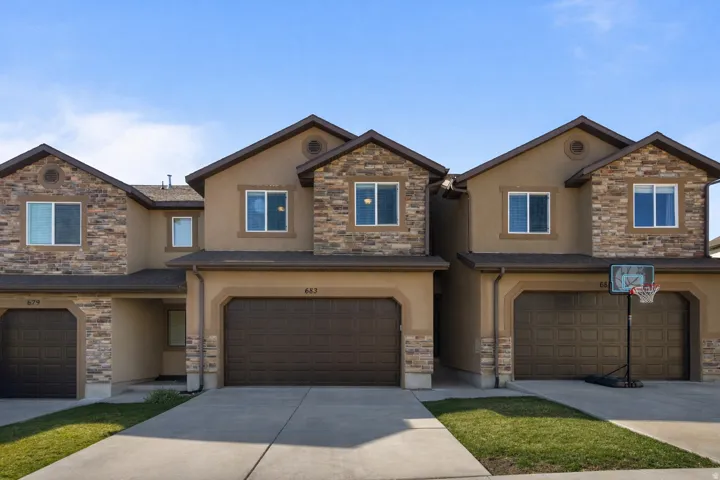 Craftsman-style house featuring stucco siding, stone siding, and driveway