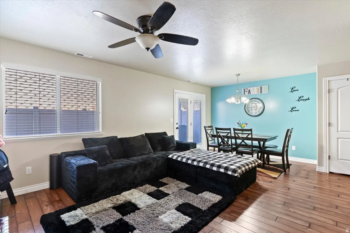 Living area with hardwood / wood-style floors, ceiling fan, a textured ceiling, and hanging lights